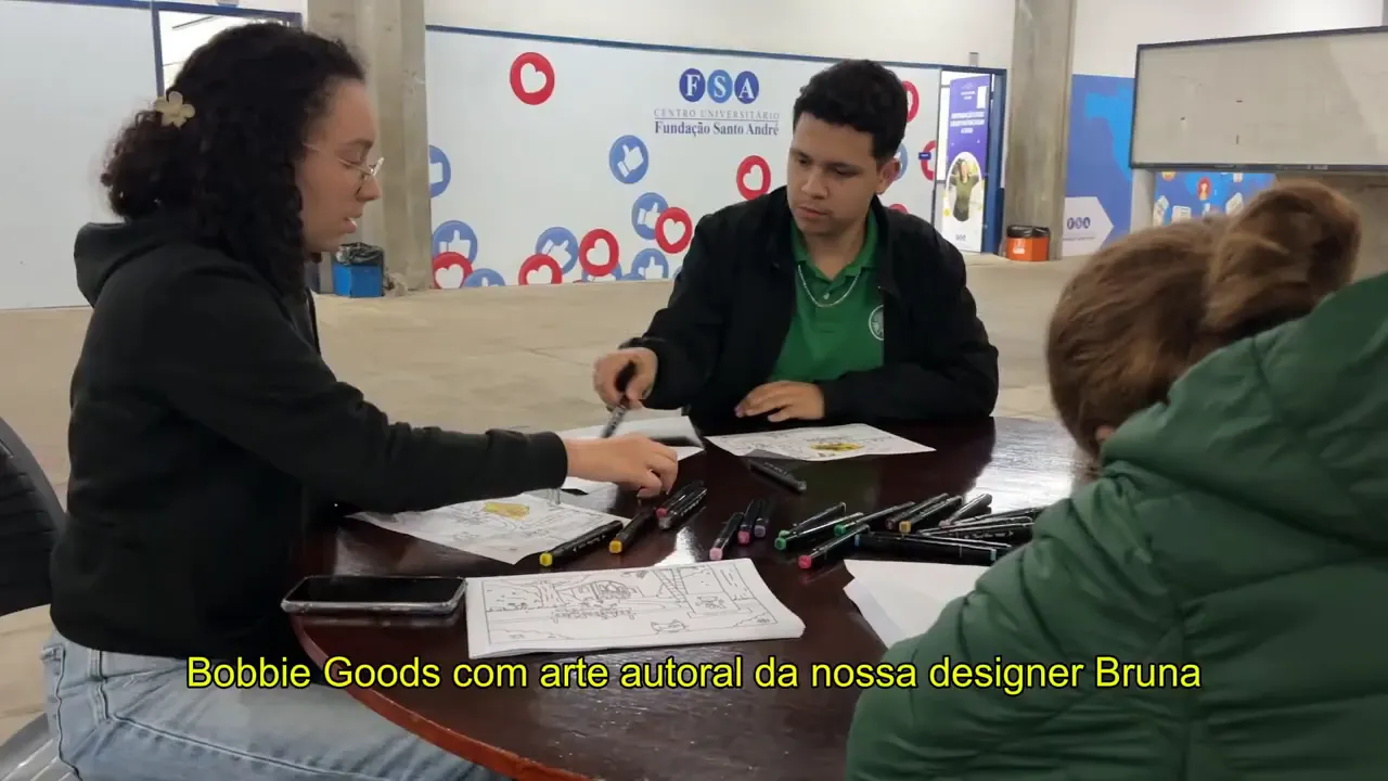Alunos sentados em volta de uma mesa colorindo ilustrações com canetas marcadoras — oficina de Bobs com arte da designer Bruna.