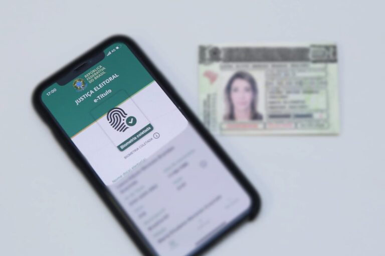 e-Título aberto em celular ao lado de título de eleitor